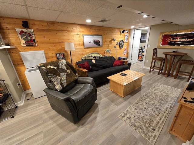 living room featuring a paneled ceiling, wood walls, and wood-type flooring