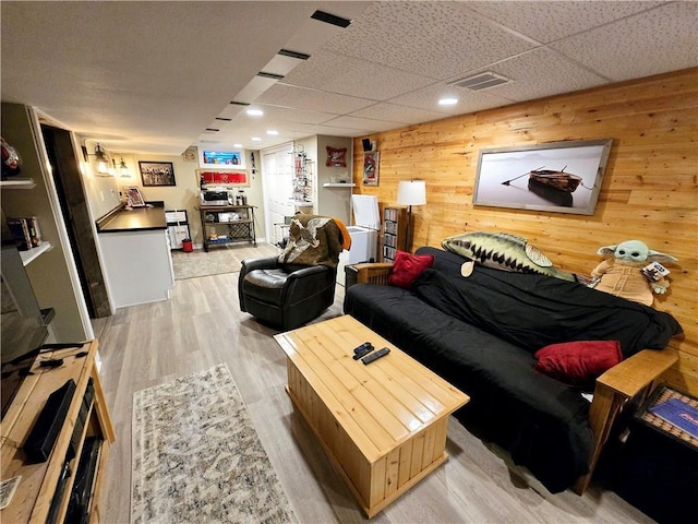 living room with light hardwood / wood-style floors and wood walls