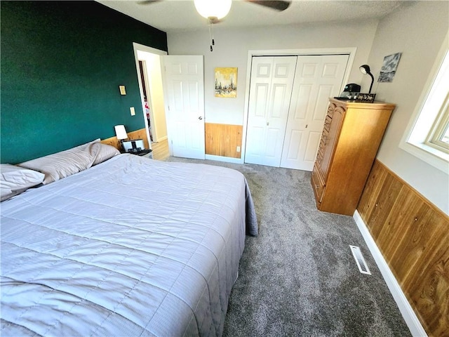 bedroom with a closet, ceiling fan, light carpet, and wooden walls