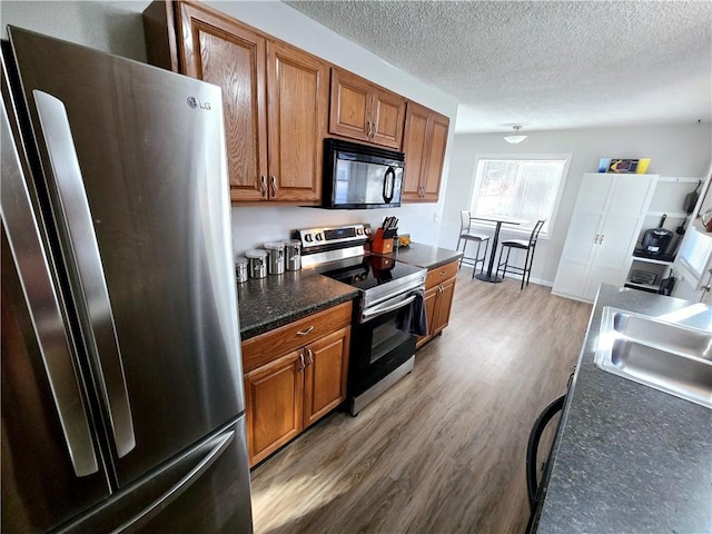 kitchen featuring hardwood / wood-style flooring, appliances with stainless steel finishes, sink, and a textured ceiling