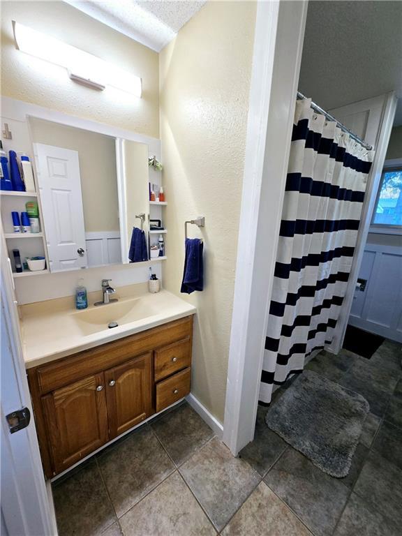 bathroom with vanity, a textured ceiling, walk in shower, and tile patterned flooring