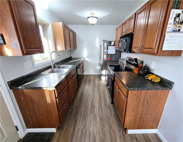 kitchen featuring appliances with stainless steel finishes, a textured ceiling, sink, and dark wood-type flooring