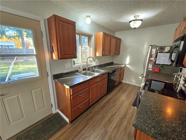 kitchen with sink, wood-type flooring, a textured ceiling, and black appliances