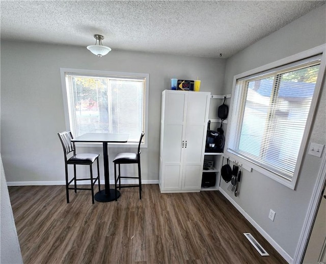 dining area with dark hardwood / wood-style floors and a textured ceiling