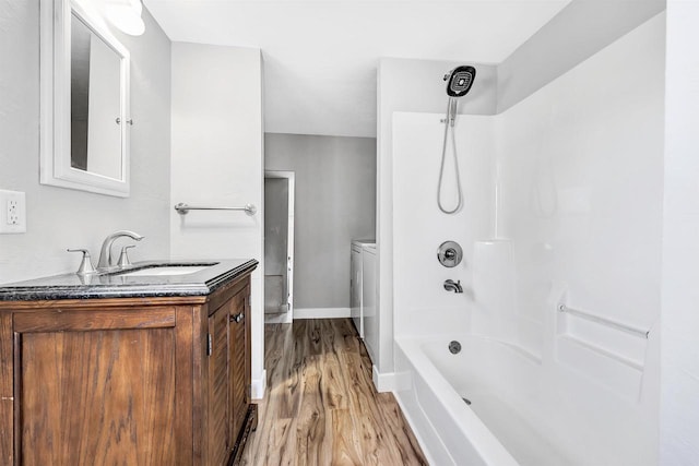 bathroom featuring washer / dryer, vanity, shower / tub combination, and hardwood / wood-style flooring