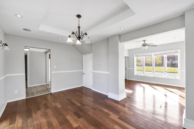 interior space with dark wood-type flooring, ceiling fan with notable chandelier, and a raised ceiling