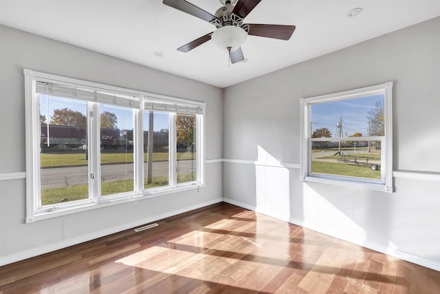 spare room with ceiling fan, wood-type flooring, and a wealth of natural light