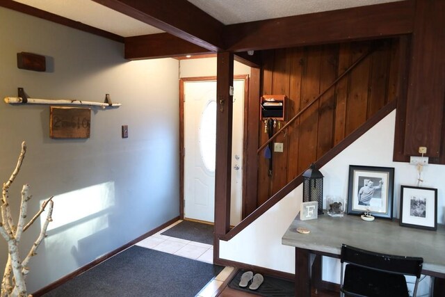 tiled entryway with beamed ceiling