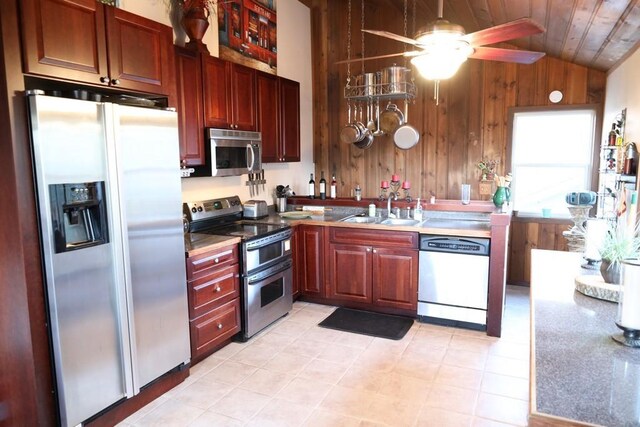 kitchen with appliances with stainless steel finishes, sink, wooden ceiling, vaulted ceiling, and wooden walls