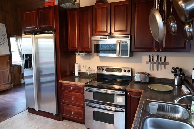 kitchen with appliances with stainless steel finishes, sink, and light wood-type flooring