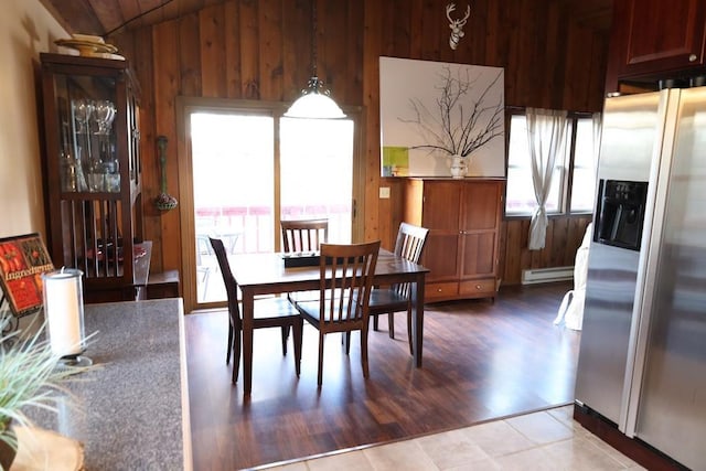 dining area featuring baseboard heating, wooden walls, and light hardwood / wood-style floors