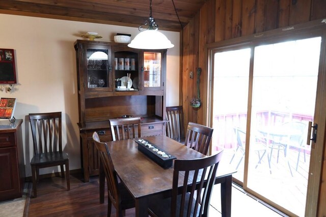 dining area featuring wood ceiling, wood walls, and dark wood-type flooring