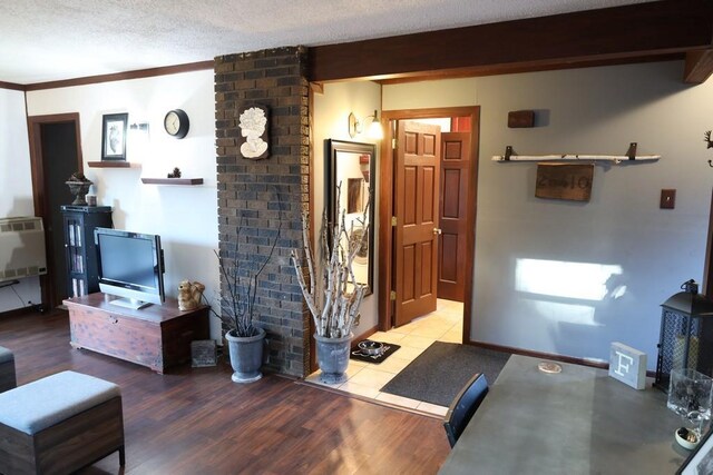 living room featuring beam ceiling, hardwood / wood-style floors, crown molding, heating unit, and a textured ceiling