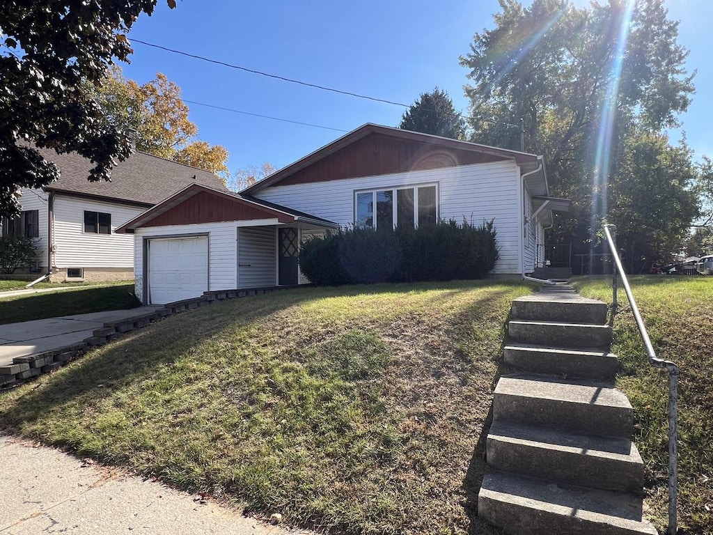 single story home featuring a garage, a front lawn, and an outbuilding