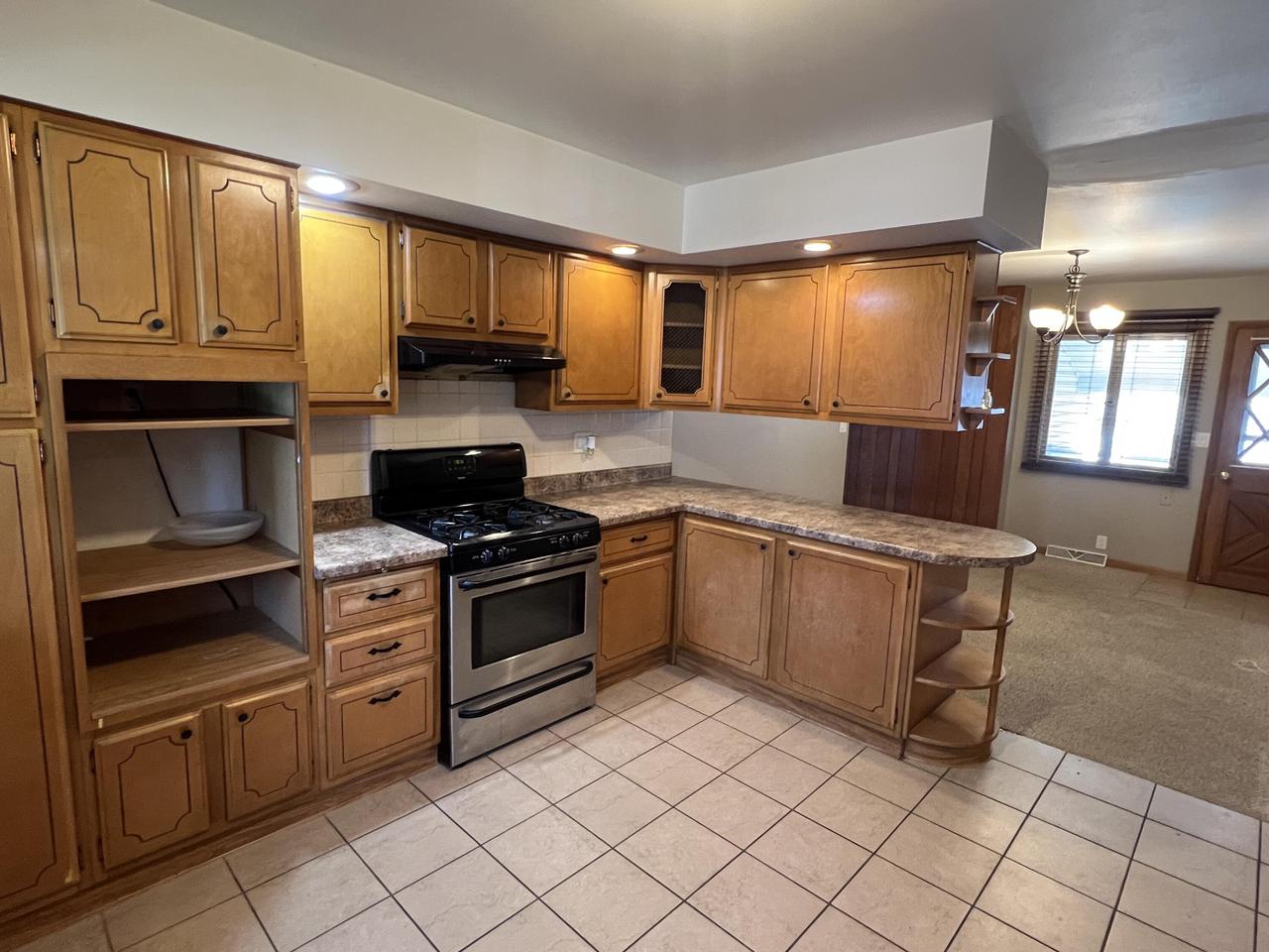 kitchen with gas stove, light tile patterned floors, a chandelier, and hanging light fixtures