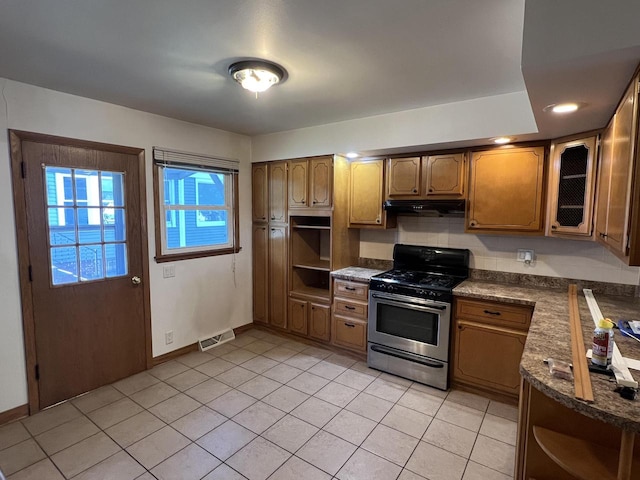 kitchen with stainless steel range with gas cooktop, dark stone counters, and light tile patterned floors