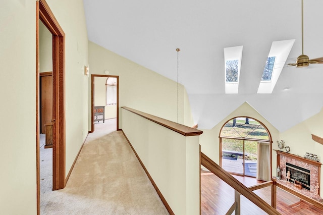 corridor with vaulted ceiling with skylight and light colored carpet