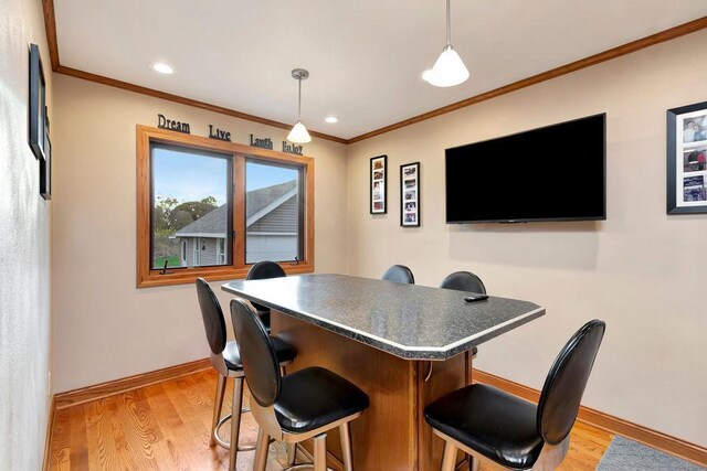 interior space with crown molding, light hardwood / wood-style flooring, and pendant lighting