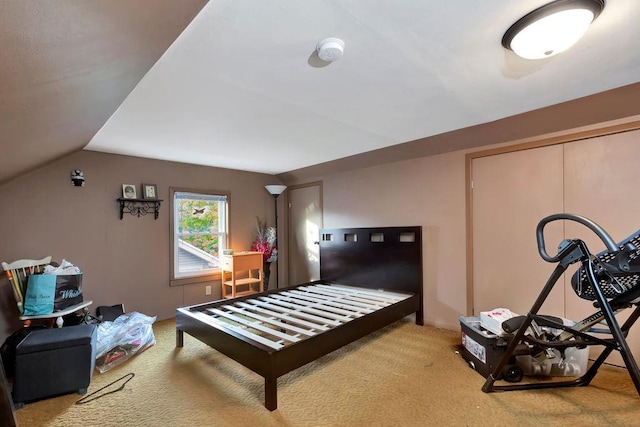 bedroom featuring a closet, lofted ceiling, and light colored carpet