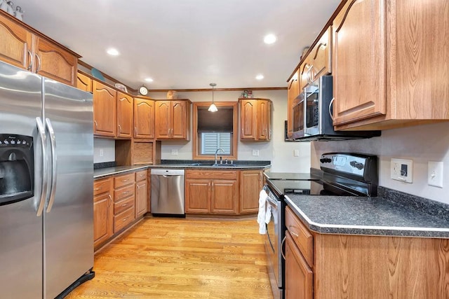 kitchen with appliances with stainless steel finishes, sink, pendant lighting, ornamental molding, and light hardwood / wood-style flooring