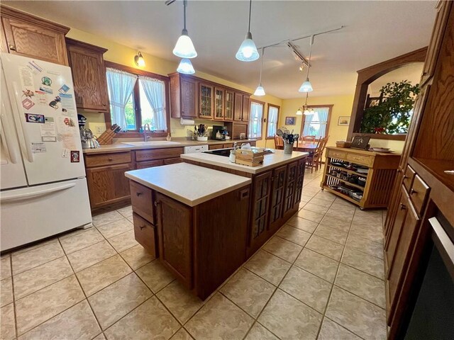 kitchen featuring sink, a center island, pendant lighting, light tile patterned floors, and white fridge