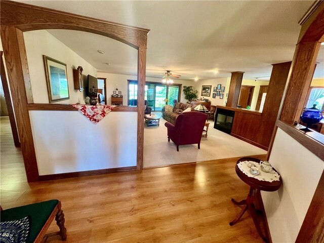 interior space with ceiling fan, decorative columns, and light wood-type flooring