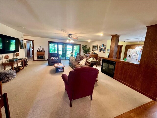 carpeted living room featuring decorative columns and ceiling fan