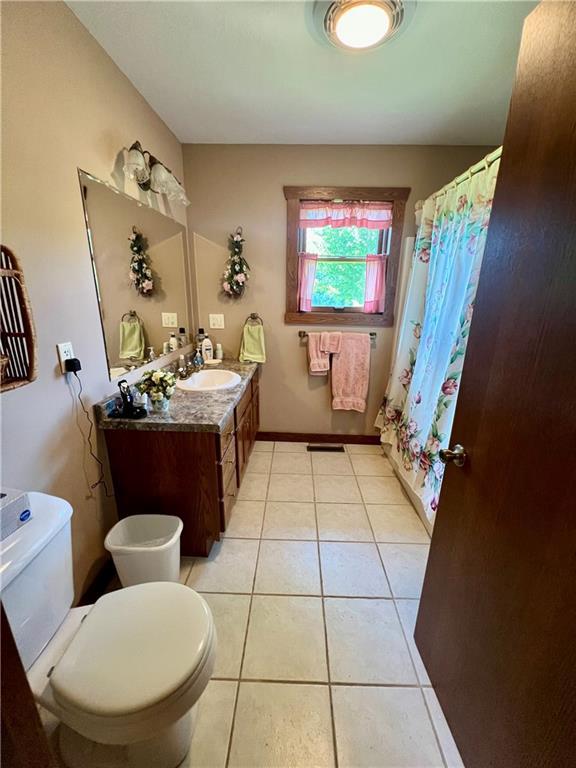 bathroom featuring vanity, a shower with shower curtain, toilet, and tile patterned flooring