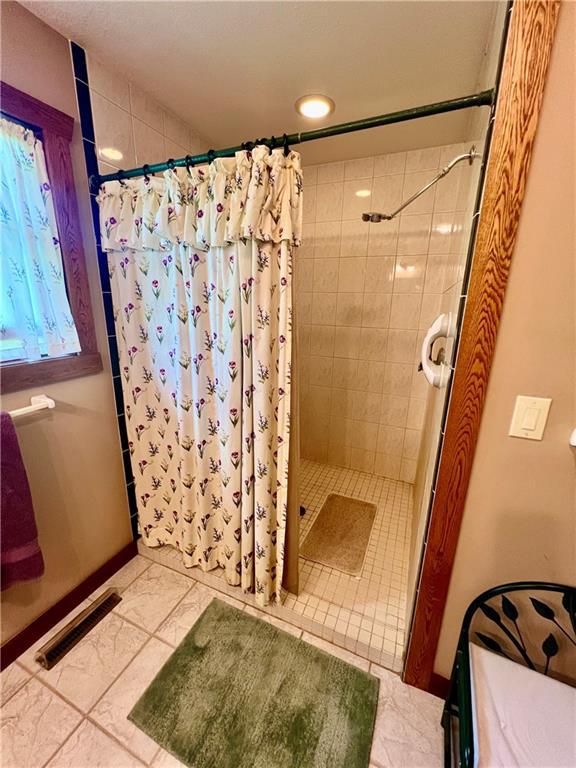 bathroom with walk in shower and tile patterned floors