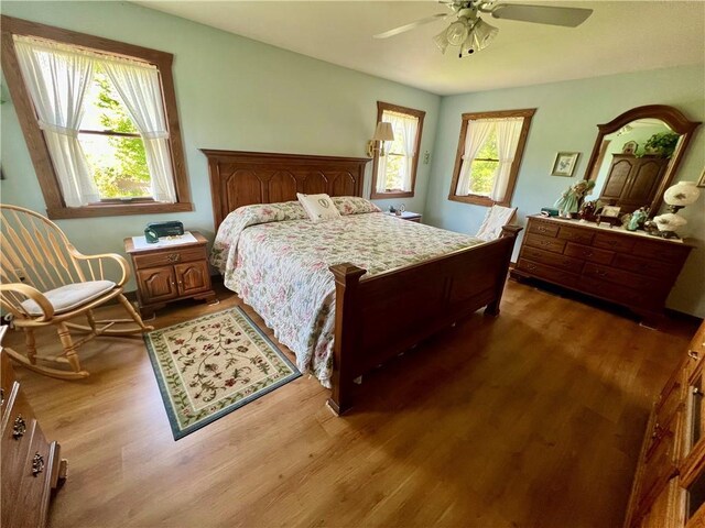 bedroom with hardwood / wood-style floors, multiple windows, and ceiling fan