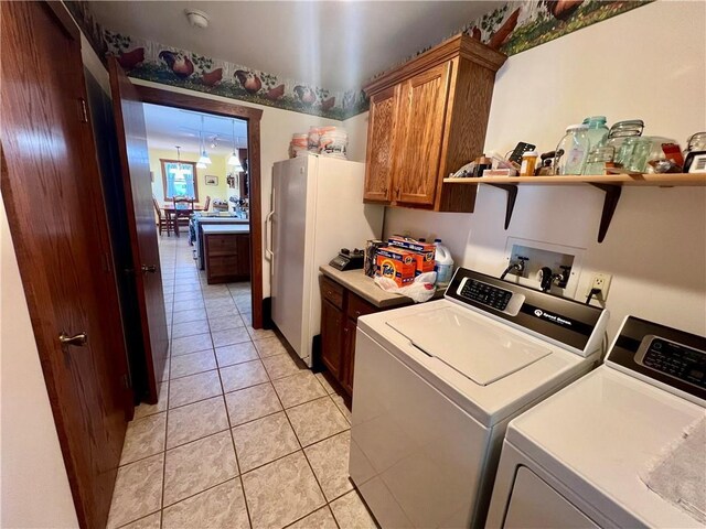 clothes washing area featuring cabinets, light tile patterned flooring, and washing machine and dryer