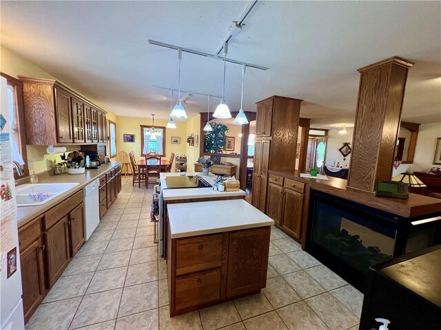 kitchen with white appliances, light tile patterned flooring, a kitchen island, rail lighting, and decorative light fixtures