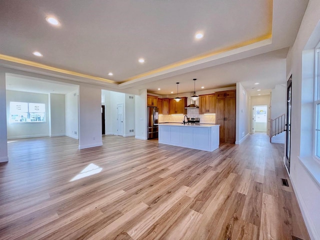 unfurnished living room with a tray ceiling and light hardwood / wood-style floors