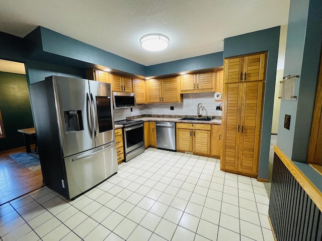 kitchen featuring sink, stainless steel appliances, light tile patterned floors, and tasteful backsplash