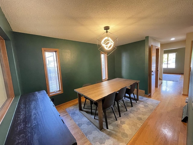 dining room with a notable chandelier, a textured ceiling, and light hardwood / wood-style flooring