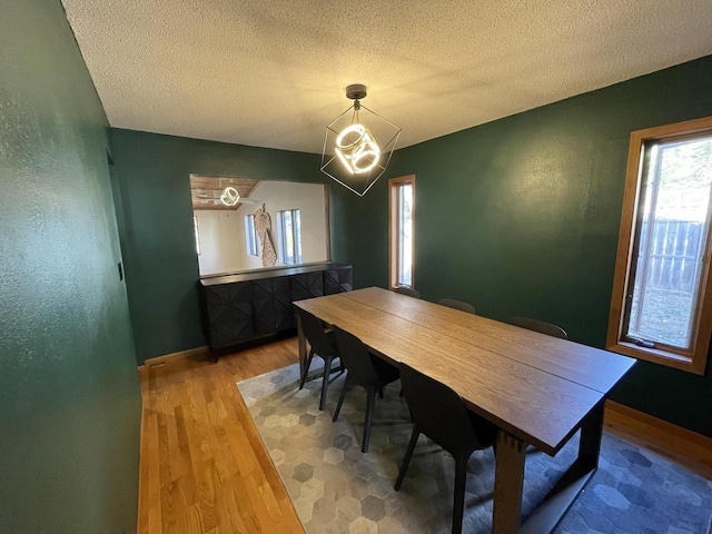 dining space with a notable chandelier, hardwood / wood-style flooring, and a textured ceiling