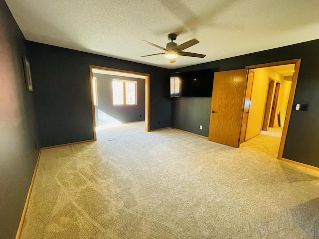 unfurnished bedroom with light carpet, a textured ceiling, and ceiling fan