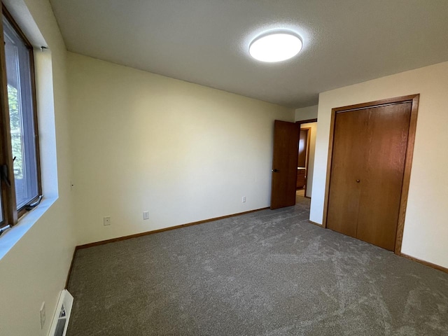 unfurnished bedroom with dark colored carpet, a textured ceiling, and a closet