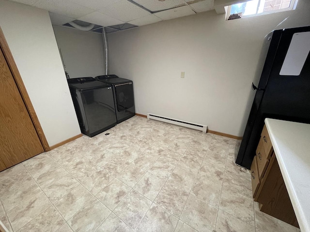 laundry area featuring light tile patterned floors, a baseboard radiator, and washing machine and clothes dryer