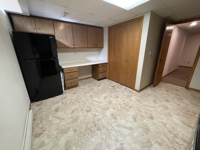 kitchen featuring a paneled ceiling, built in desk, black refrigerator, and a baseboard radiator