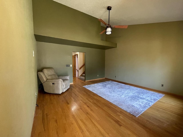 interior space with ceiling fan, high vaulted ceiling, a textured ceiling, and light wood-type flooring