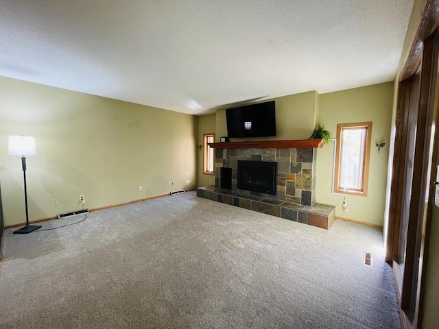 unfurnished living room with carpet, a stone fireplace, and a textured ceiling