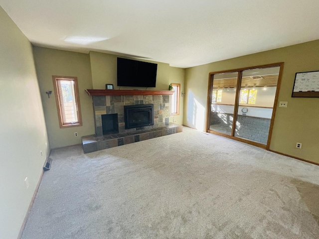 unfurnished living room with carpet flooring and a tile fireplace