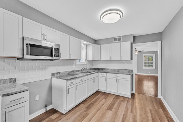 kitchen with white cabinetry, ceiling fan, light wood-type flooring, and a wealth of natural light