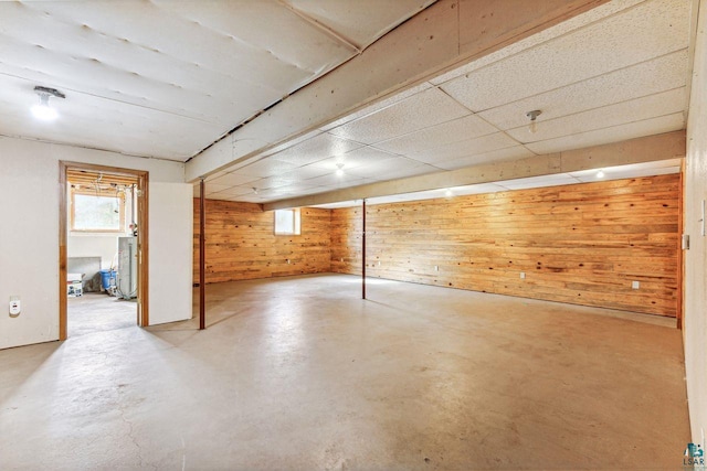 basement featuring water heater and wooden walls