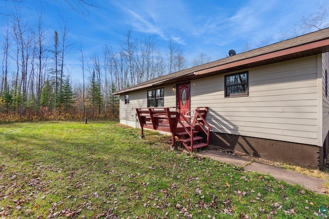 rear view of house featuring a wooden deck and a lawn