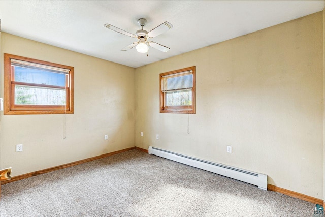 carpeted spare room with baseboard heating, a wealth of natural light, and ceiling fan