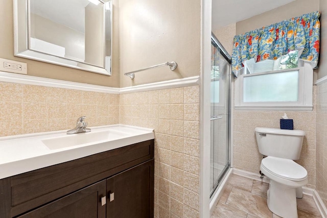 bathroom with vanity, toilet, tile walls, and a shower with shower door