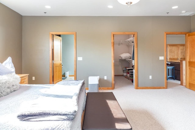 bedroom with a closet, a spacious closet, carpet flooring, and ensuite bath