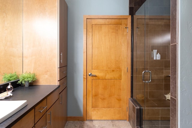 bathroom featuring vanity, a shower with shower door, and tile patterned flooring